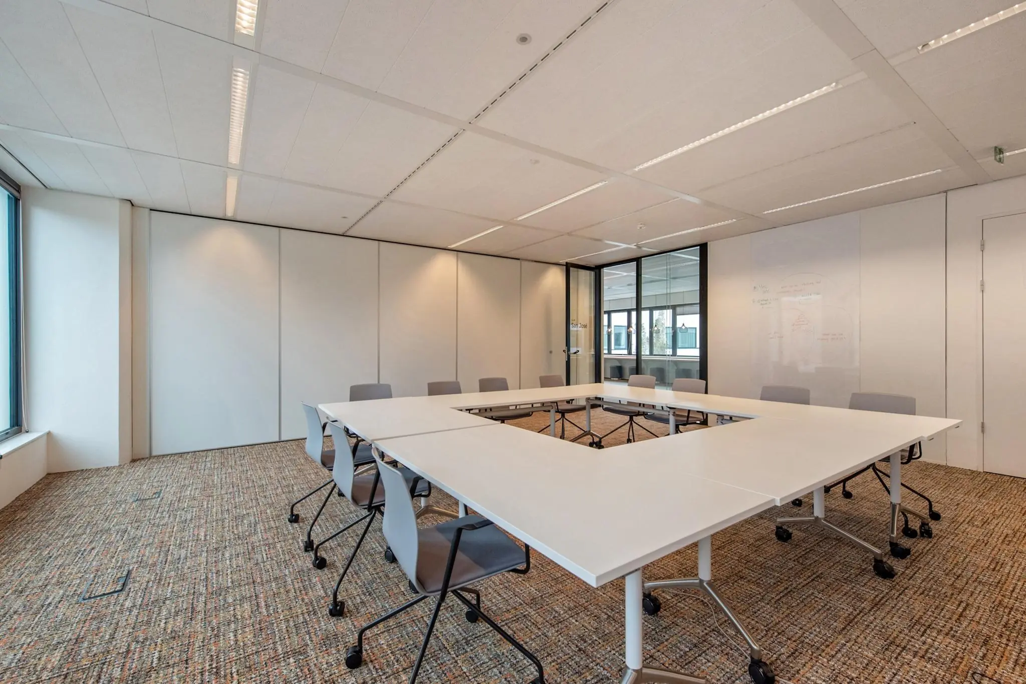 Moderne vergaderruimte in een kantoor aan de Grote Marktstraat met een U-vormige opstelling van tafels en grijze stoelen.